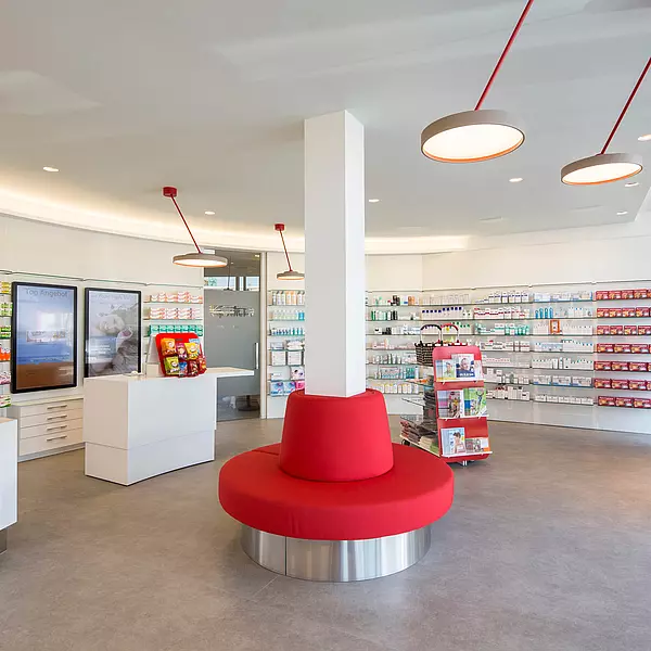 Blickfang im halbkreisförmigen Apothekenverkaufsraum die kreisförmige Bank im Zentrum.
