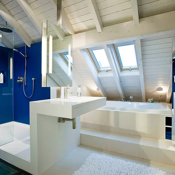 Moderne, puristische Badausstattung. Duschwände sind mit großen, blauen Fliesen aus Porzellan verkleidet. Dusche und Waschtisch bestehen aus einem Stück und bilden eine zusammenhängende Einheit. Das Material ist HIMACS.